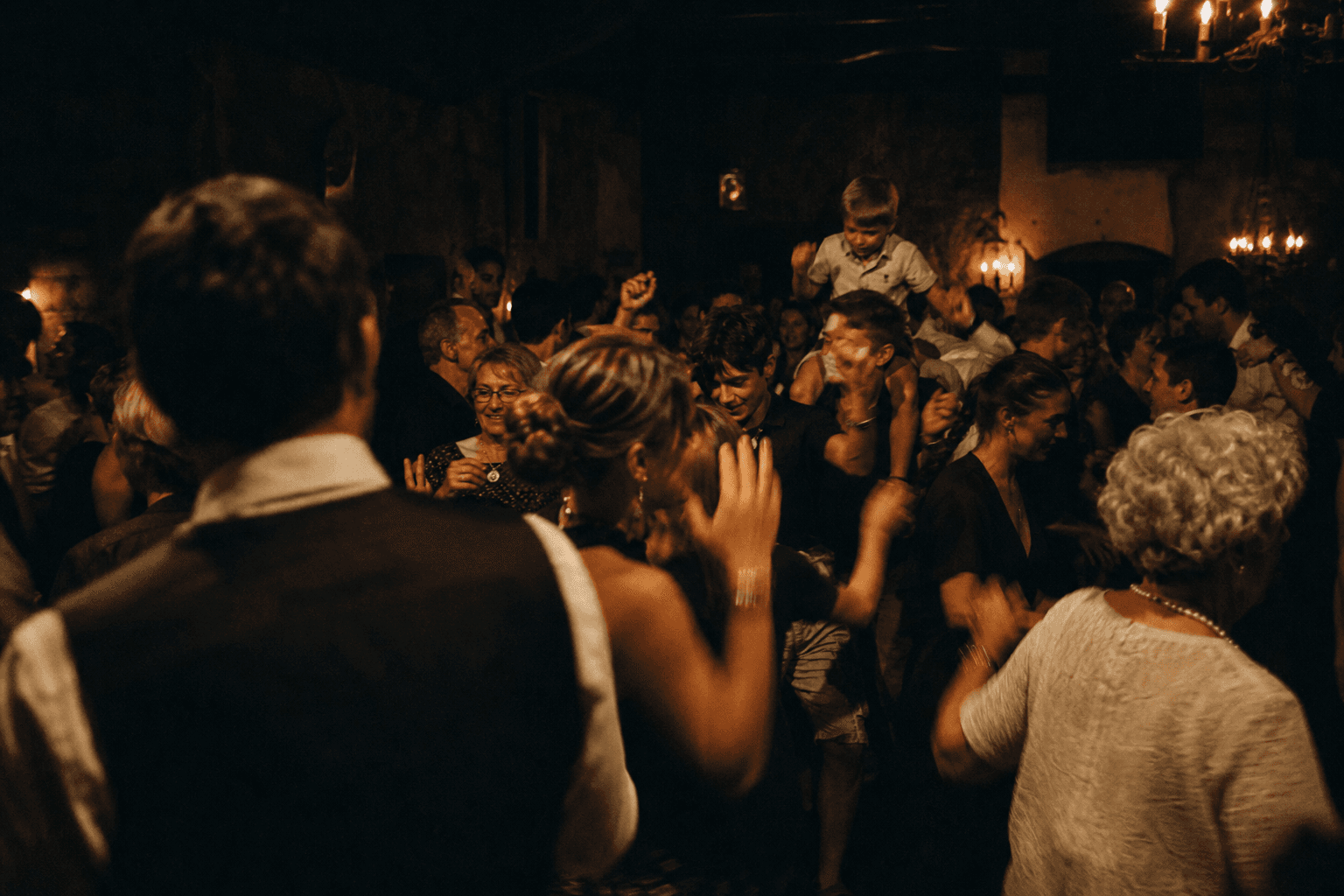 A full dance floor at 23:00, three generations dancing together under candlelight.